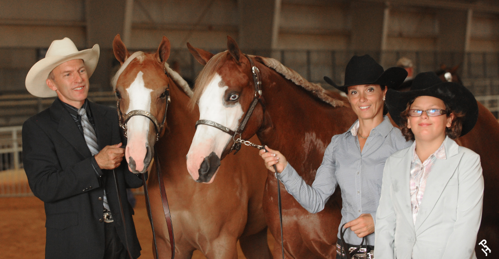 Three APHA members smiling with two Paint Horses.