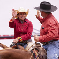 Two APHA members high five each other while horseback.