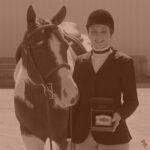 An APHA member and their horse smiling proudly with their trophy buckle.