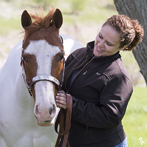 An owner lovingly petting their Paint Horse.