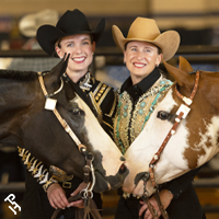 Two amateur exhibitors smiling with their horses.