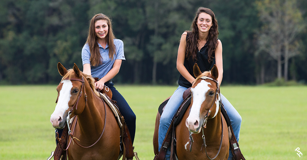 Two Paint Horse memberships smiling while horseback.